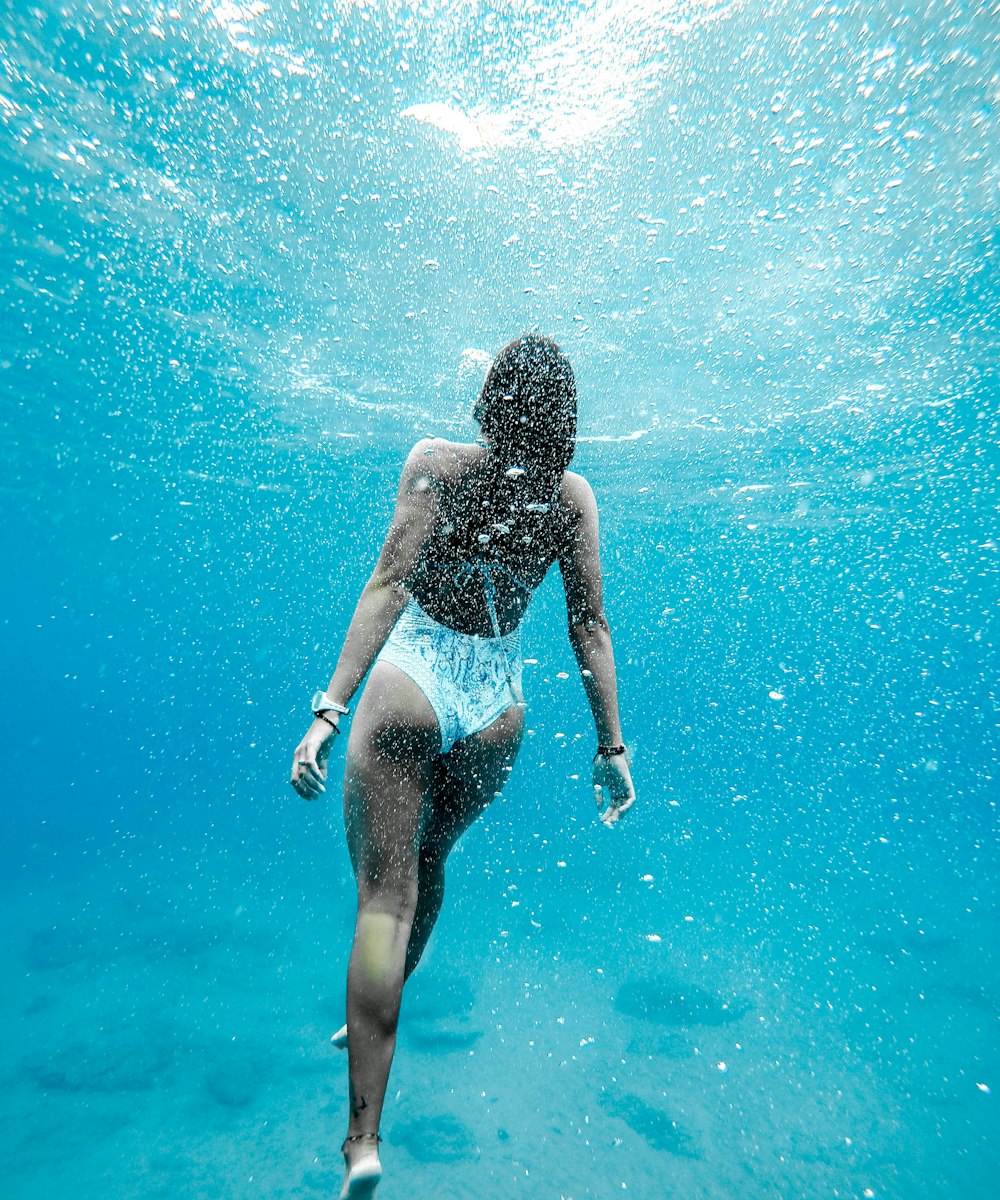 A woman gliding underwater in a clear blue pool