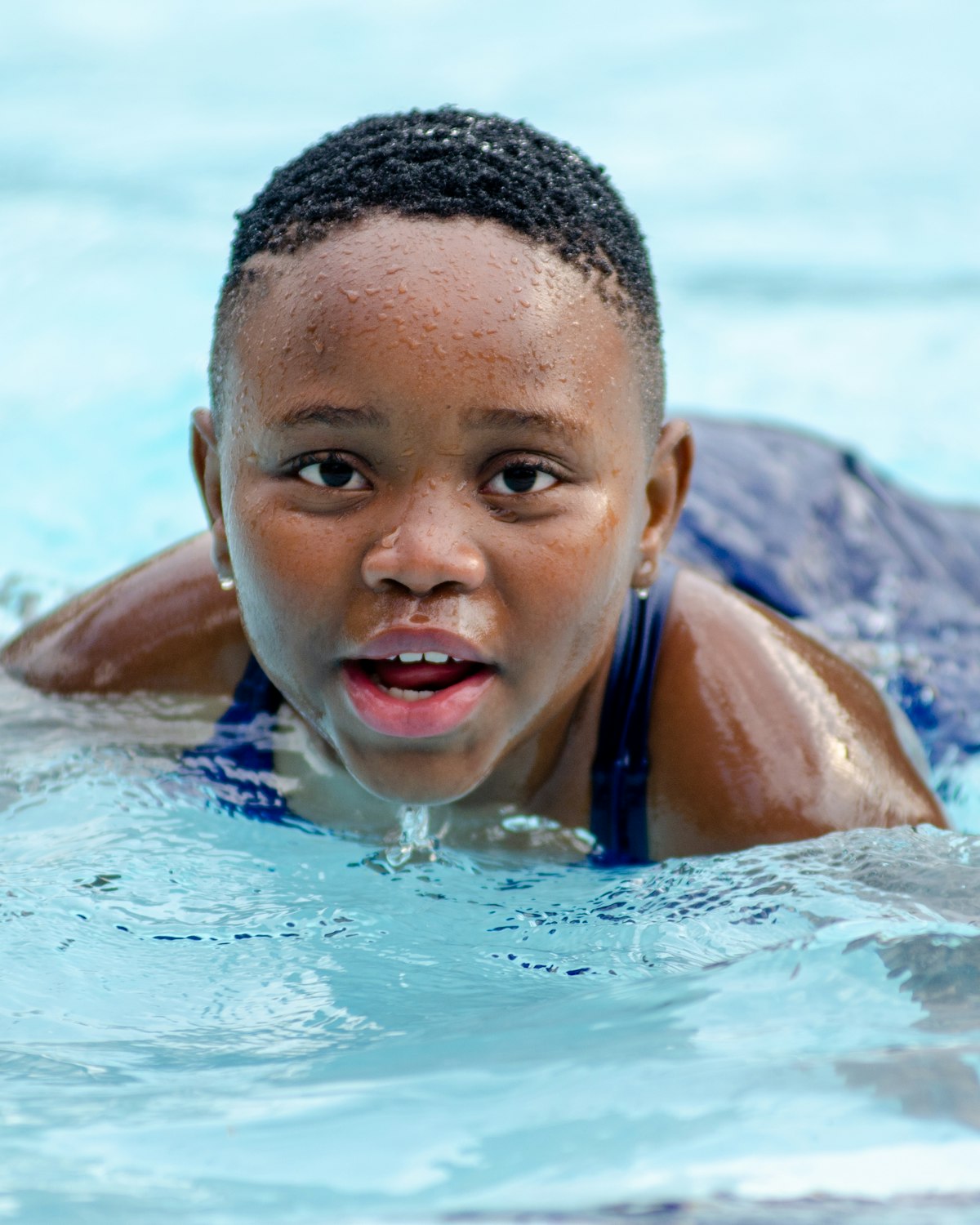A smiling boy swimming in a bright blue pool