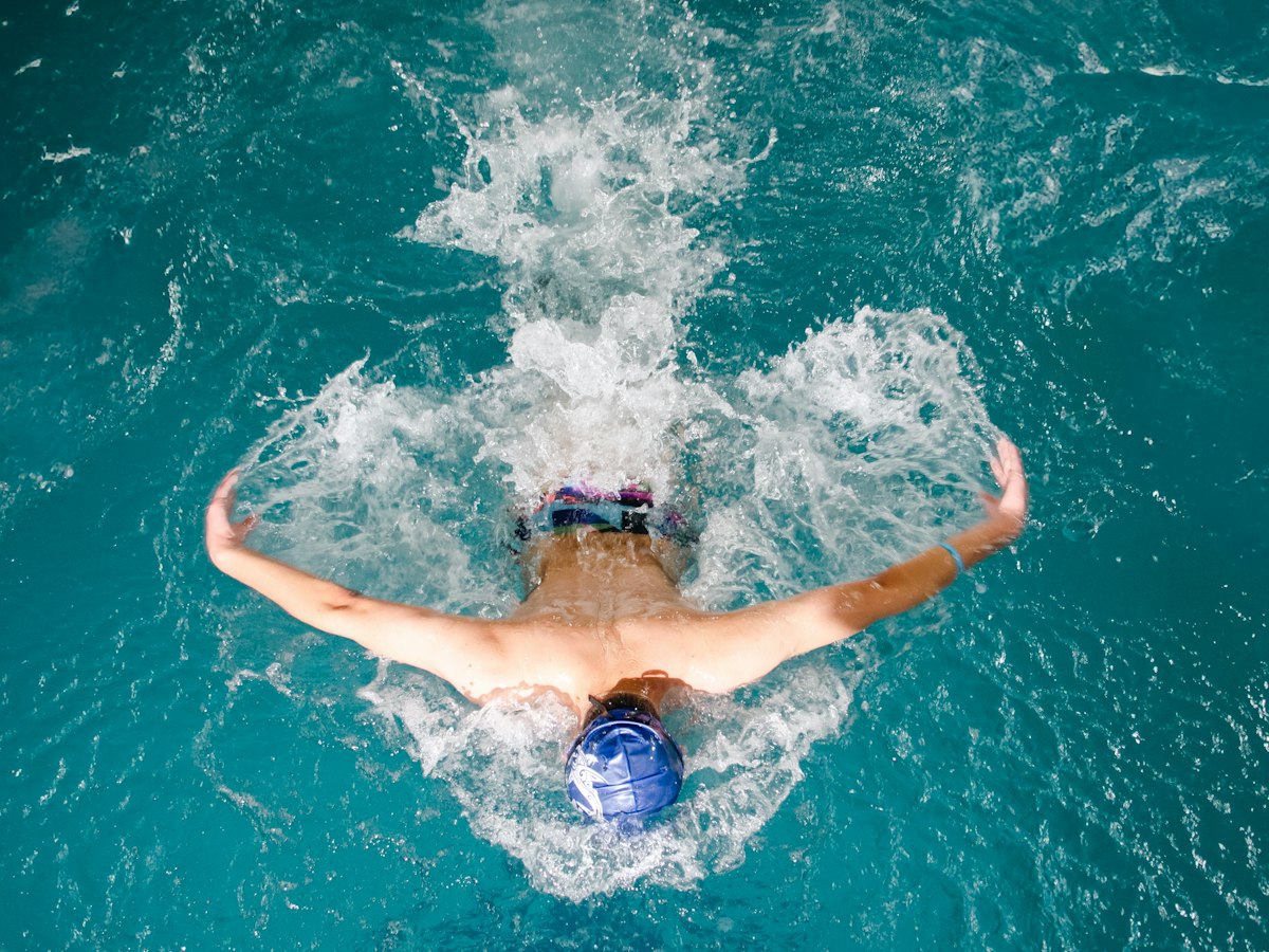 A swimmer mid butterfly stroke, water spraying off the arms