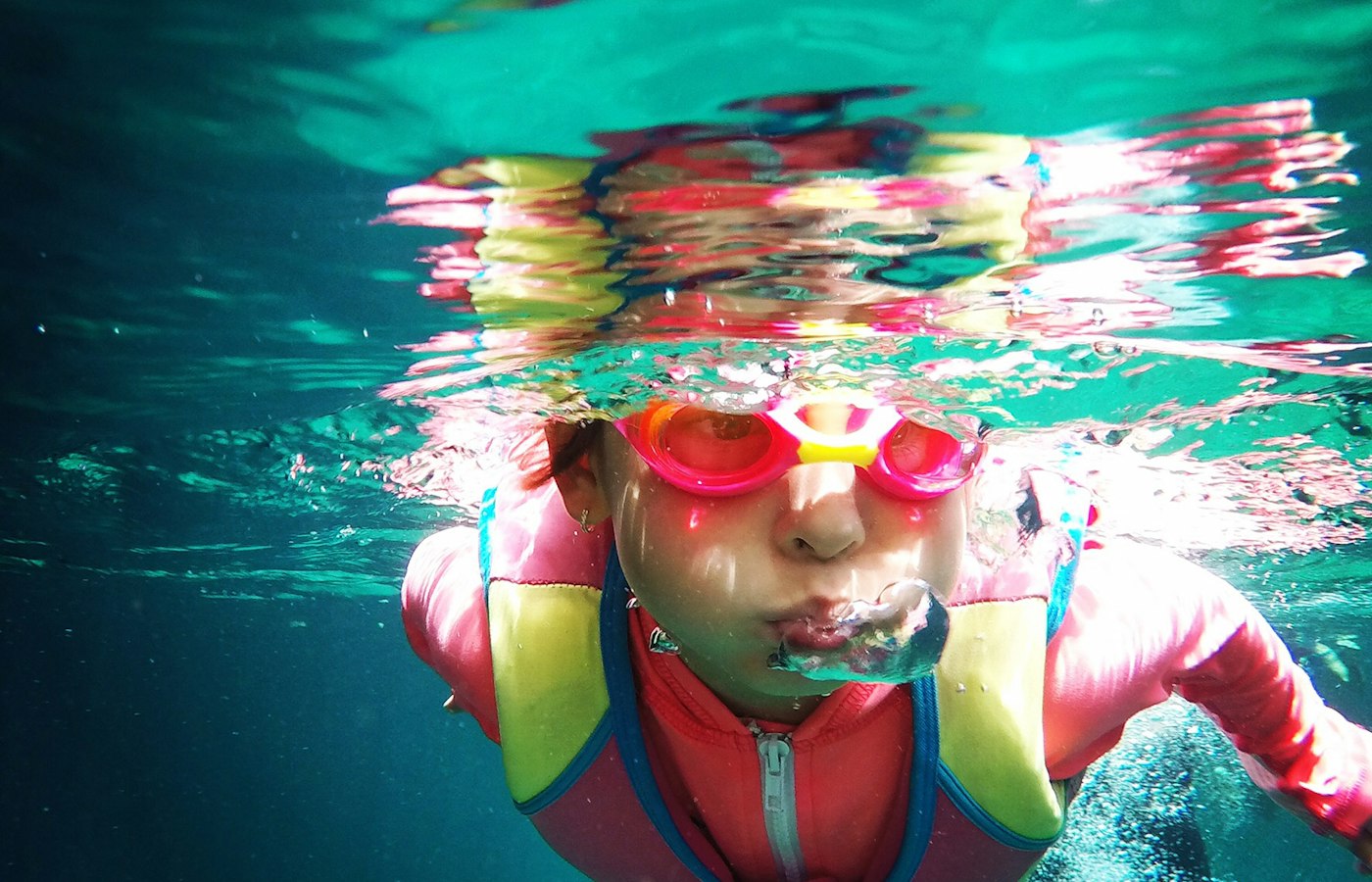 A child in pink goggles swimming underwater