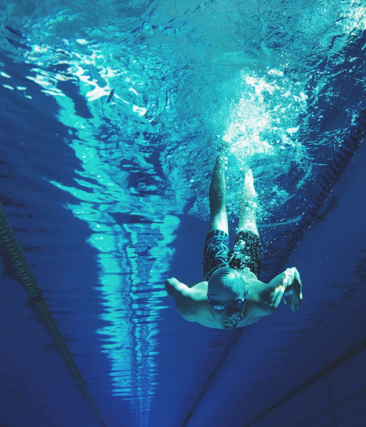 A swimmer gliding underwater along a lane